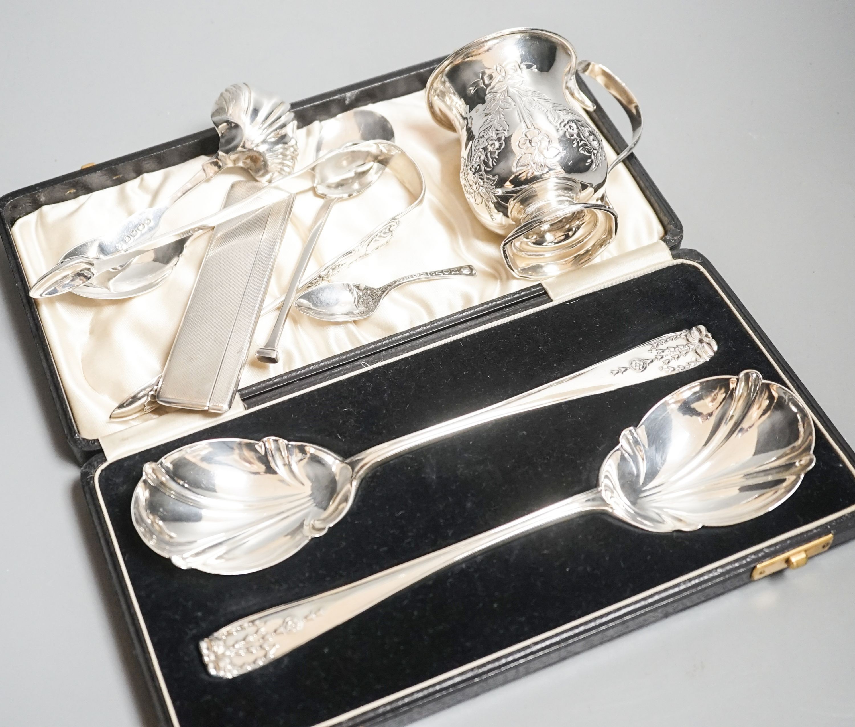 A cased pair of silver serving spoons, a silver christening mug and minor silver flatware, comb, etc.